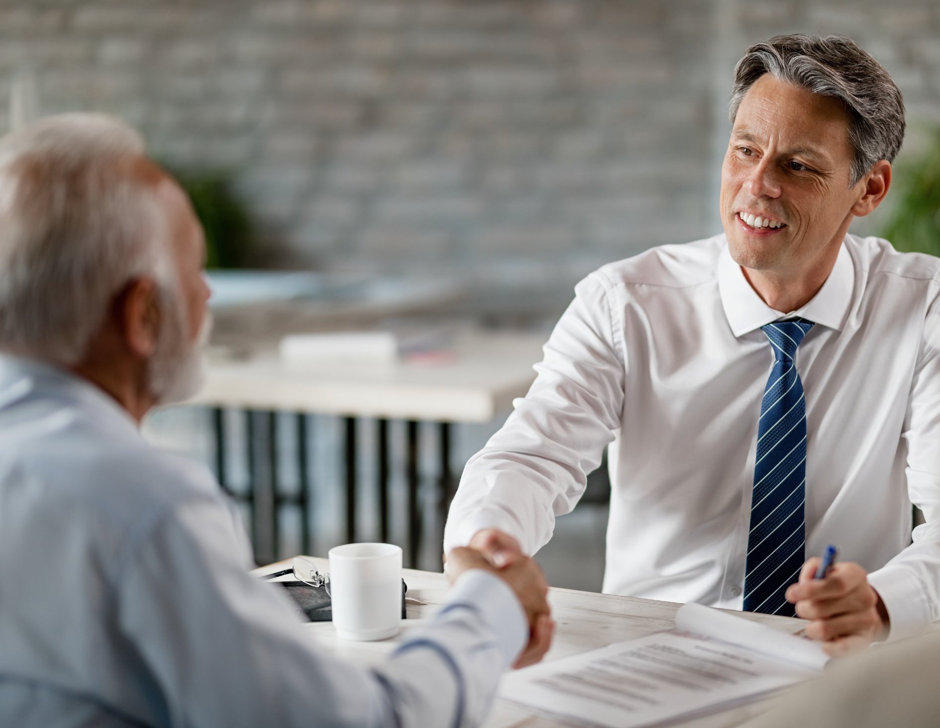 A broker shaking hands with a client across a table