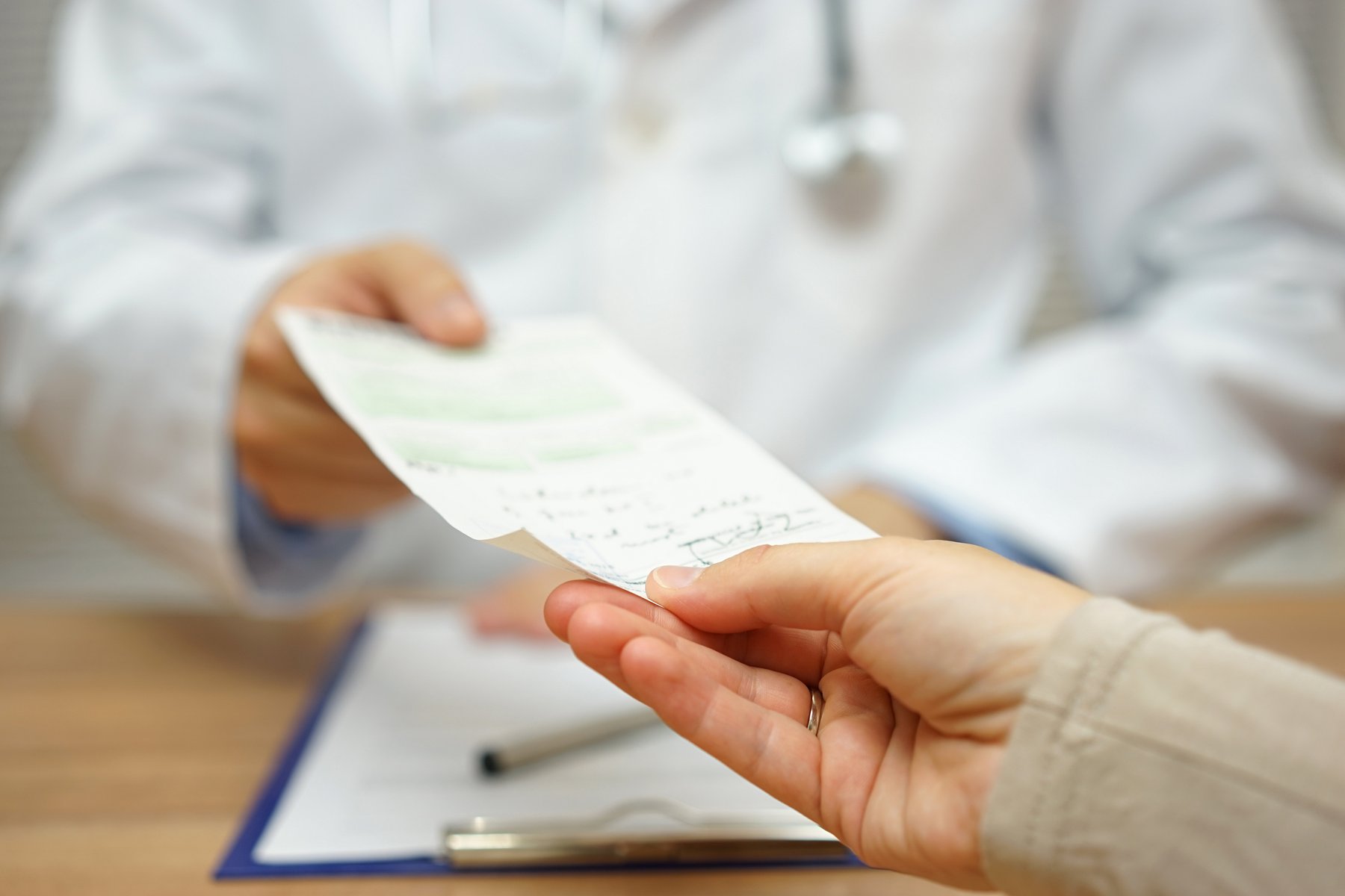 A clinician handing a prescription to a patient